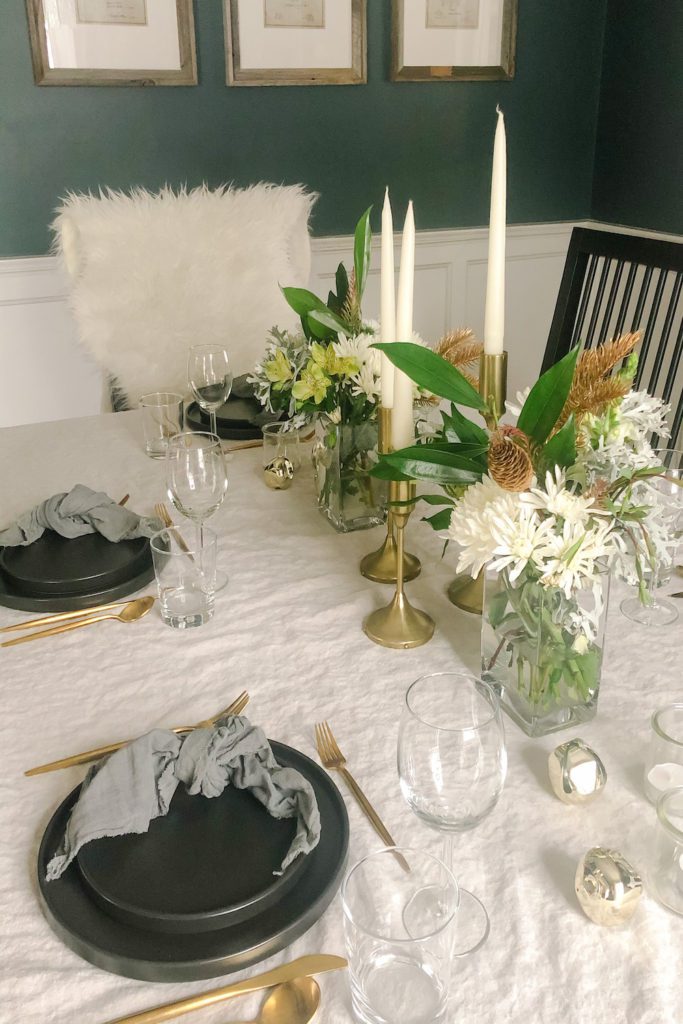 table setting with winter floral arrangement and brass taper candle centerpiece
