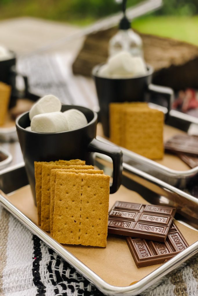 small metal cookie sheets filled with graham crackers marshmallows and chocolate on a table