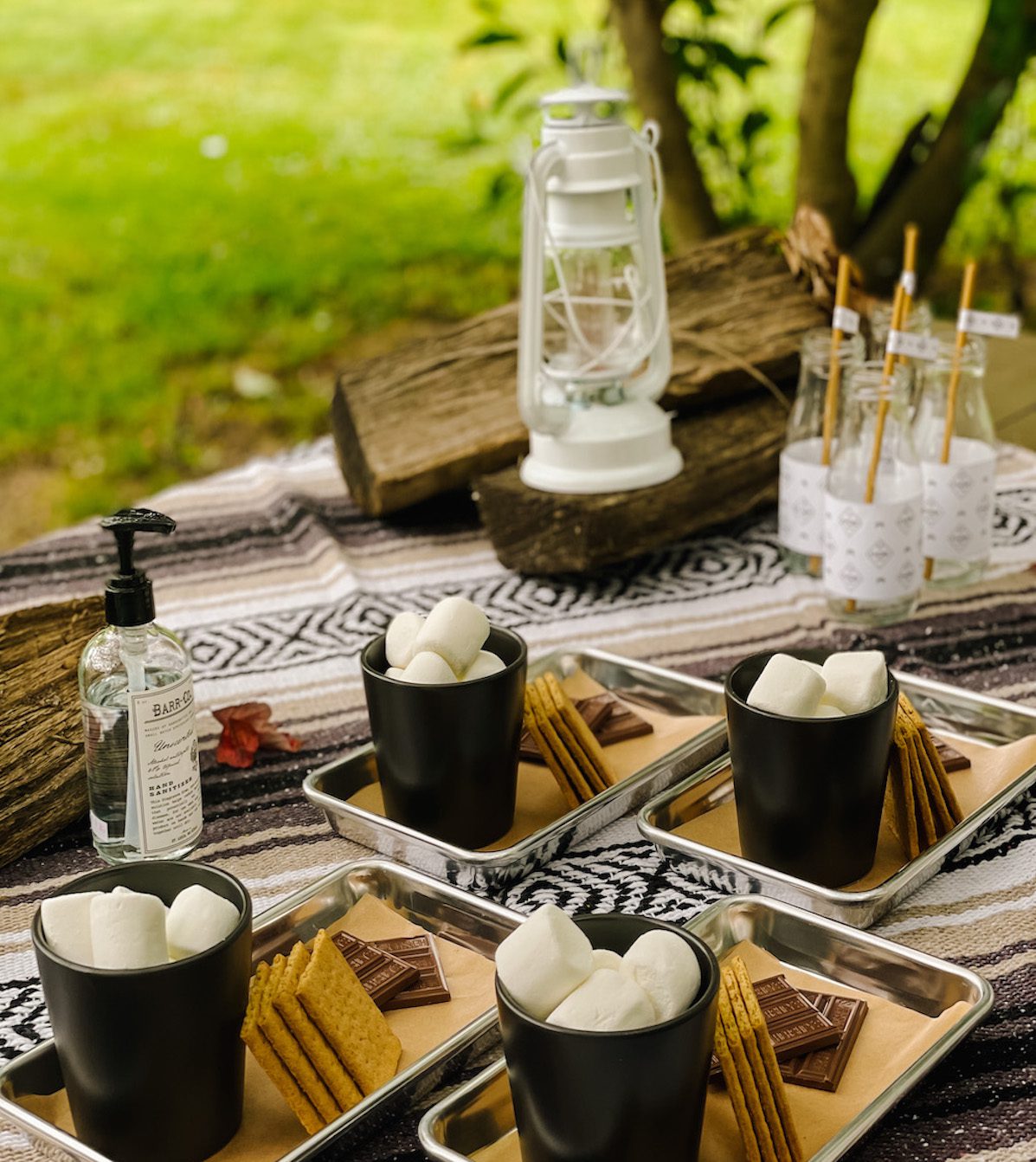 outdoor table at bonfire with plates of smores and lantern