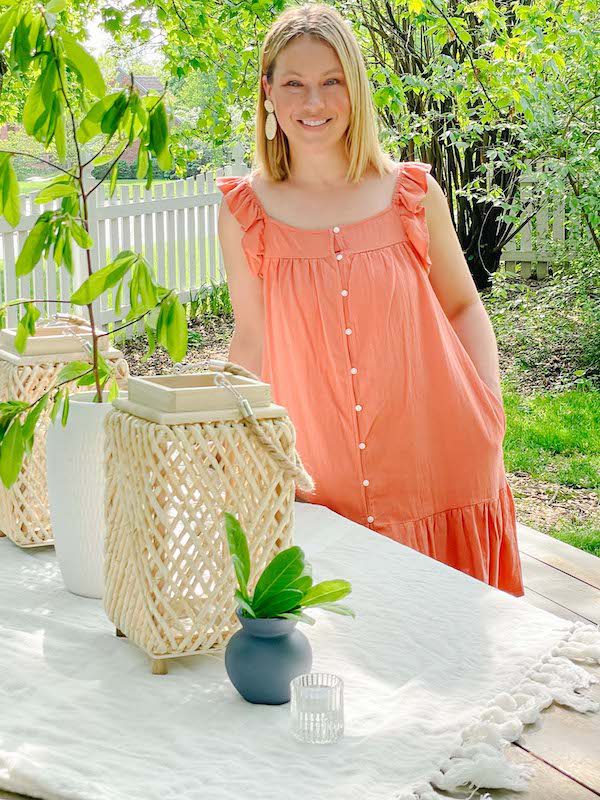 woman in sundress by a table set for summer dinner party